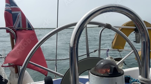 A sailing boat autopilot steering a yacht sailing downwind in light airs. The motor inside the wheel turns the wheel to keep the sailing vessel on its designated course.