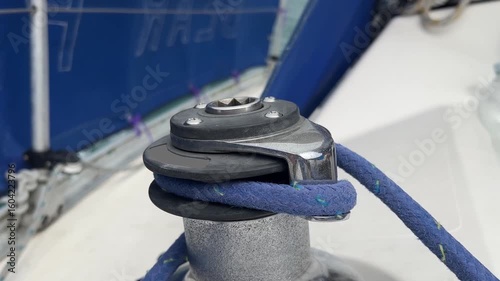 A self tailing genoa winch on a sailing yacht with a sheet wound onto it, sailing in light sunny winds