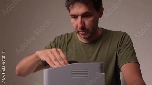 A focused man cleaning a device with a cloth for proper maintenance and cleanliness