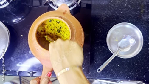 Homemaker prepares grain flakes into mud pot