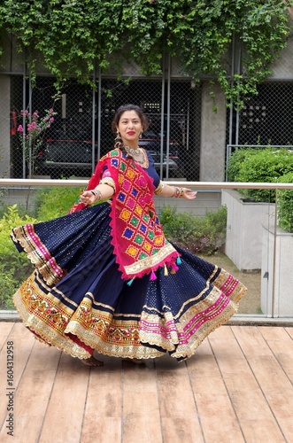 Indian - gujarati woman twirling in full flair chaniya choli with colorful dupatta, ready for Navratri for playing garba. Traditional outfit with kanch kachhi laces and mirror embroideries