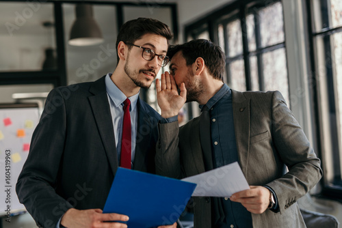 Konstfotografi Businessmen whispering and sharing confidential information in office