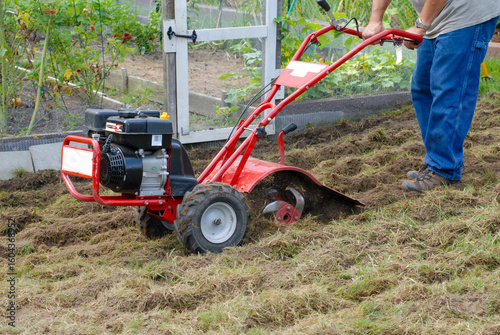 Man tilling a new garden with small motorized  plow machine. Expanding garden. rototiller. 