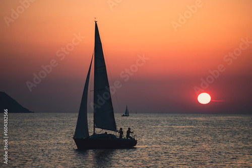 Sailing boat silhoutted against the orange sky