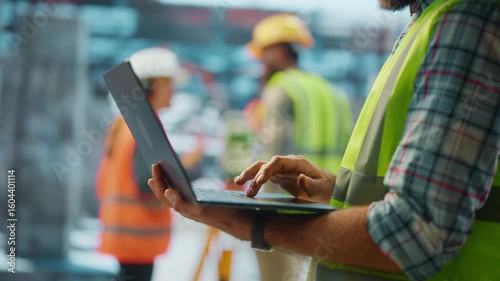 Construction engineer typing on laptop at building site
