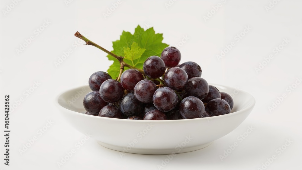 Fresh cluster of black grapes placed in a bowl on white Fresh cluster of black grapes placed in a bowl on white