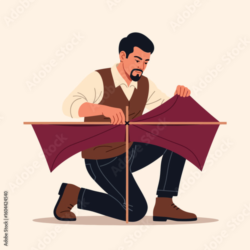 Man Kneeling Constructing Maroon Kite with Wooden Frame Indoors