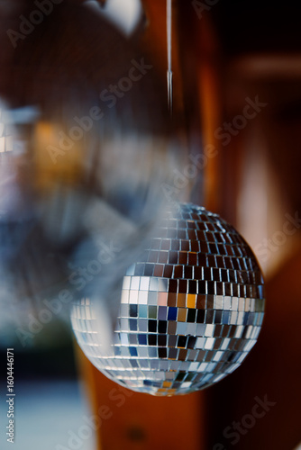 Mirrored disco balls are suspended on strings from wooden roof of beach bar