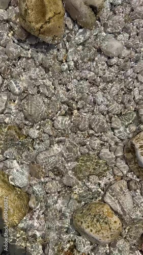 White stones under clear sea water shimmering in sunlight on island in Lastovo National Park, Croatia. Natural coastal texture and underwater tranquility.