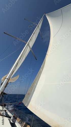 White sails filled with wind, seen from the bow of a sailing yacht near Croatia. Freedom, clean energy, adventure and mindful travel on the open sea.