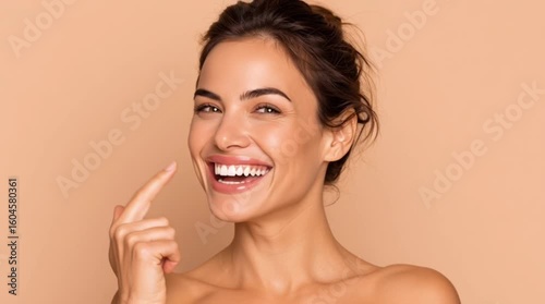 a portrait of a beautiful woman pointing at her bright, perfect smile. Her radiant smile, fresh skin radiates health, happiness, and confidence.