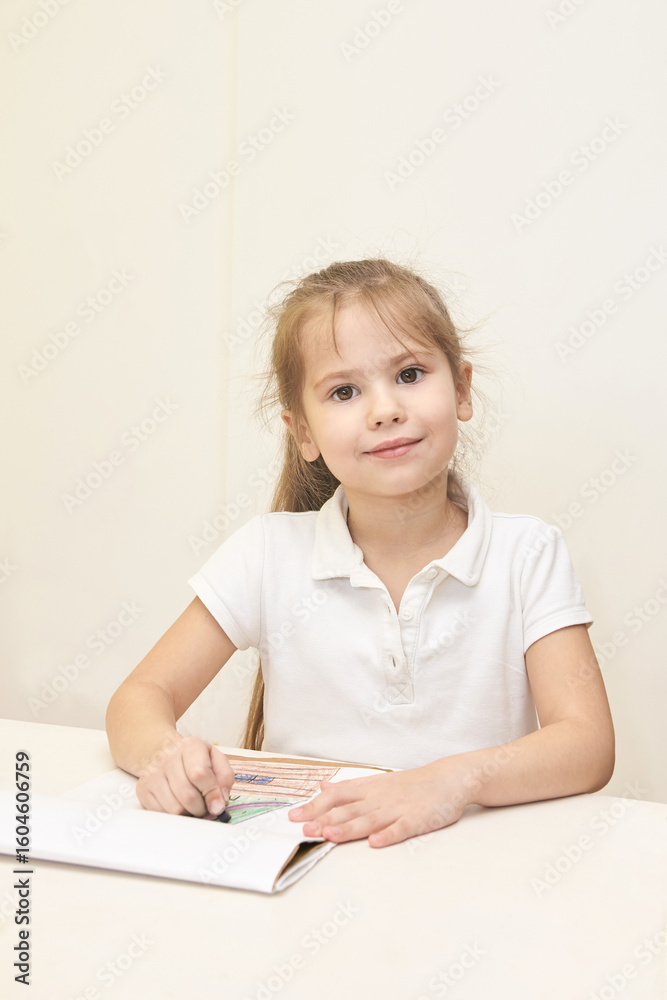 Young caucasian girl drawing with colored pencils on white paper at home desk. Young caucasian girl drawing with colored pencils on white paper at home desk.