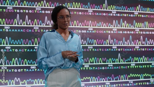 Talking businesswoman on stage in front of LED wall with graph of dna structure