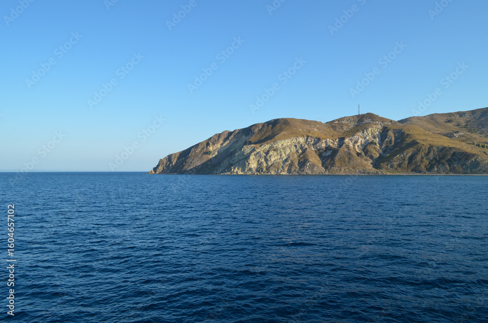 Fototapeta premium Rocky Island Coastline with Deep Blue Sea and Clear Sky