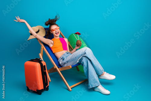 Wall Mural Happy young woman relaxing on a deck chair with sunglass, colorful outfit, and p