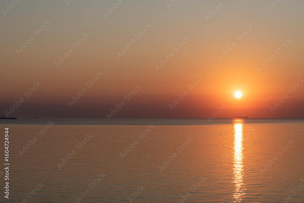 Obraz premium Sunset over calm waters with reflection creating a serene atmosphere in the evening sky