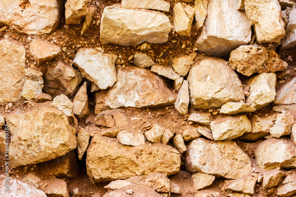 Fototapeta premium Close-Up of Natural Stone Wall with Uneven Rocks and Clay Texture