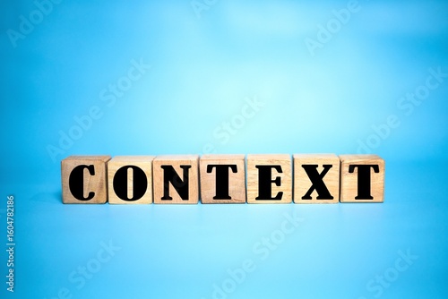 CONTEXT word on cube wood. light blue background. cube wood concept.