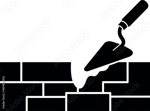 Bricklaying trowel spreading mortar on new wall construction