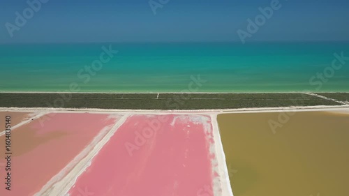 Stunning aerial view of the pink salt evaporation ponds in Las Coloradas, Mexico, contrasting with the turquoise Caribbean Sea