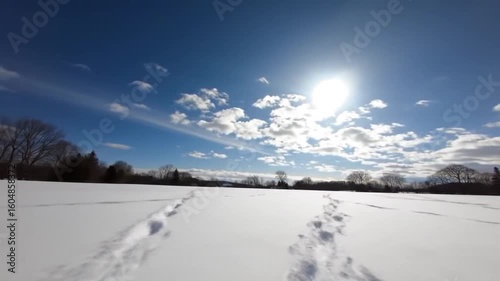 Footprints in a snow-covered field under a bright sky