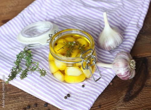 Garlic cloves pickled in olive oil and thyme. A glass jar full of garlic cloves should be kept in the refrigerator.