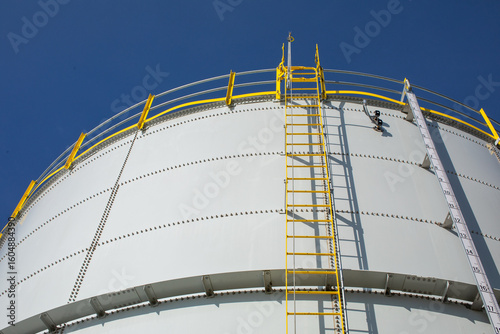 Foto looking up at large water tank with yellow stairs and blue sky