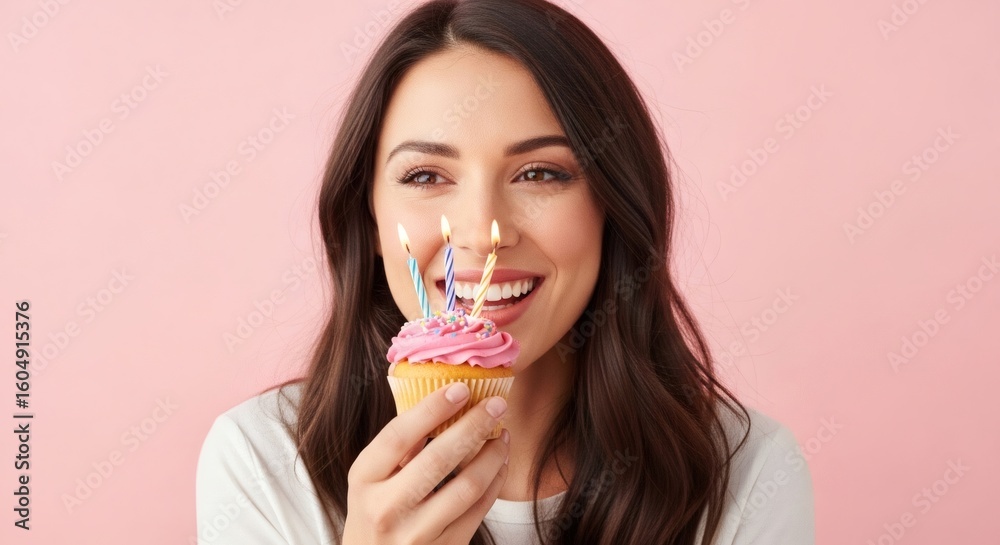 Woman celebrates her birthday with a cupcake and lit candles. Woman celebrates her birthday with a cupcake and lit candles.