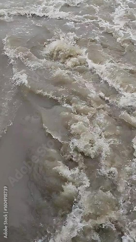Vigorous turbulent water showcasing the raw, untamed power of natural currents with swirling eddies and frothy whitecaps. This dynamic river flow illustrates the immense force of nature's relentless m