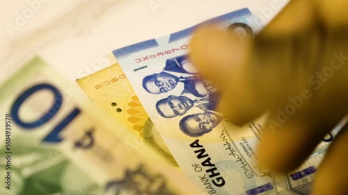 Black person hands holding counting vadious Ghanaian cedi notes denominations paper currency on white table desk background. Checking accounting cedis money