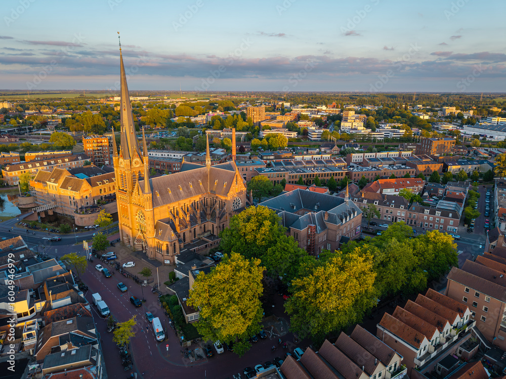 Naklejka premium Aerial cityscape of Woerden, The Netherlands, featuring historical St. Bonaventura church at sunset