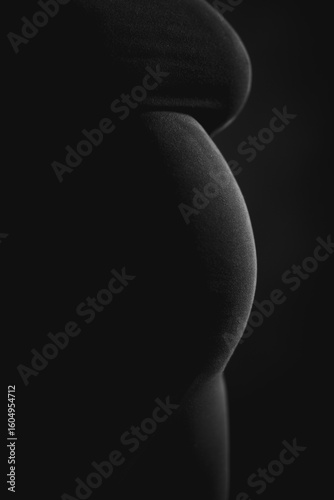 Pregnant belly silhouette on black background – minimal low-key maternity concept with copy space