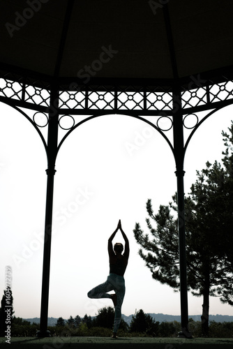 Yoga tree pose silhouette under pavilion – mindfulness and balance outdoors