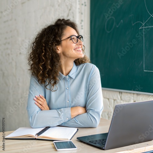 Young woman teacher with curly hair wearing glasses looking up thoughtfully