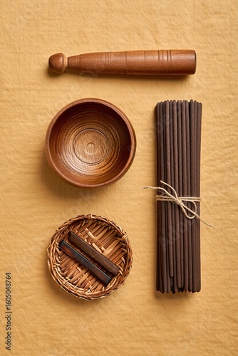 Flat lay of wooden incense tools, a carved bowl, and natural accessories on a neutral fabric background. Minimalist wellness or aromatherapy concept with natural textures.