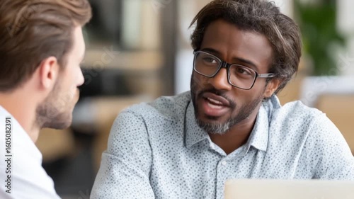 Two men in discussion, one wearing glasses, focusing on one speaker
