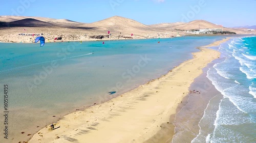 Aerial view of a crowd of kitesurfers enjoying the waves on the beach of Sotavento, Fuerteventura Island, Spain.