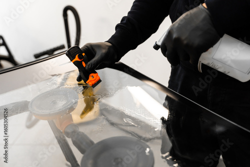 Obraz na płótnie Technician uses scraper to clean the surface of a new windshield post-replacement