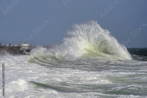 Vague éclatant en gerbe d'eau de mer lors d'une tempête hivernale en Bretagne