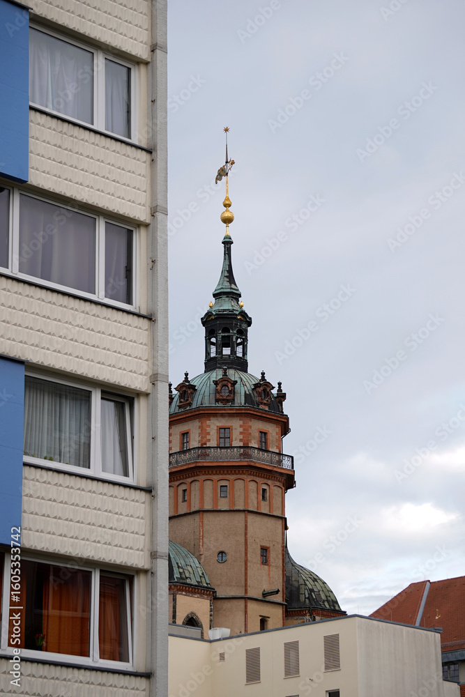 Fototapeta premium Elegant historical architecture tower. Ornate spires and rooftop details. Contrasting modern building nearby. Urban cityscape with evening sky. High resolution detailed city photo.