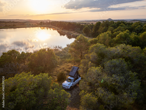 Romantic Camping at the lake with 4x4 Offroad vehicle with roof tent at sundown