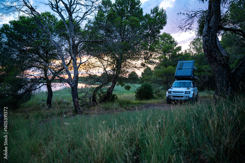 Romantic Camping at the lake with 4x4 Offroad vehicle with roof tent at sundown
