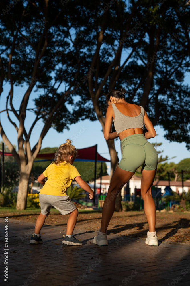 custom made wallpaper toronto digitalBack view of a fit woman and her young son exercising together in a sunny park, both squatting with energy and focus, enjoying an outdoor workout under the shade of tall trees