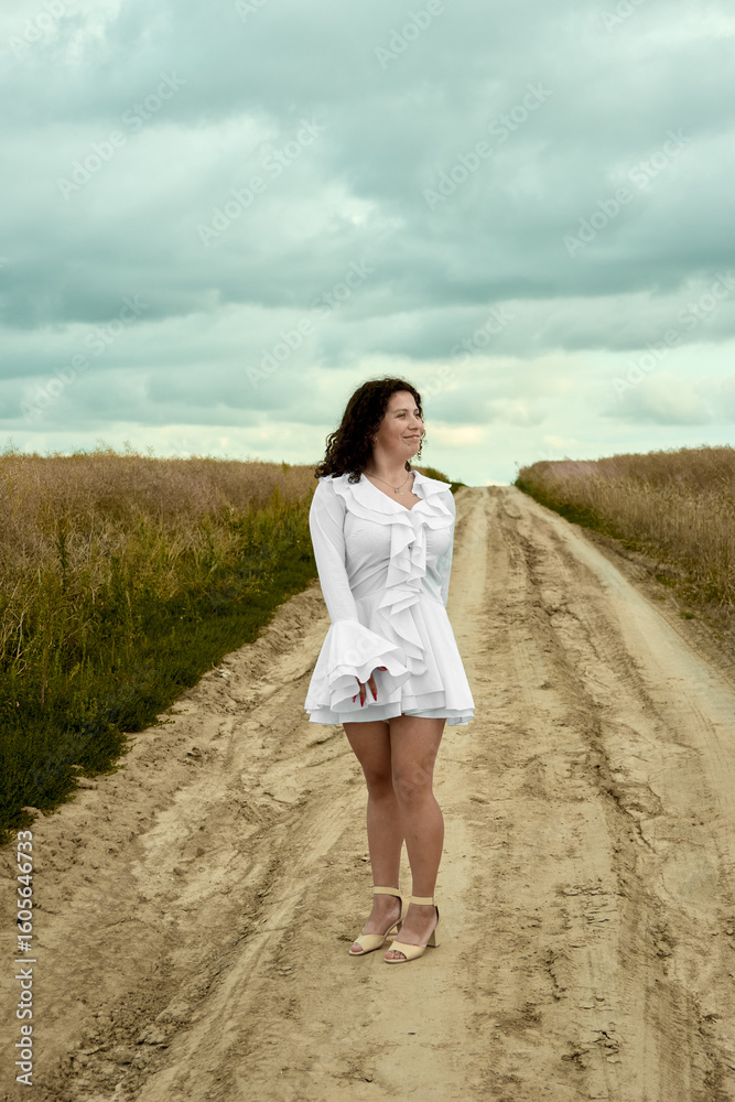 A beautiful woman in a white dress stands on a dirt road amidst a picturesque field, exuding elegance and tranquility, offering a scene of serene natural beauty and feminine grace . A beautiful woman in a white dress stands on a dirt road amidst a picturesque field, exuding elegance and tranquility, offering a scene of serene natural beauty and feminine grace .