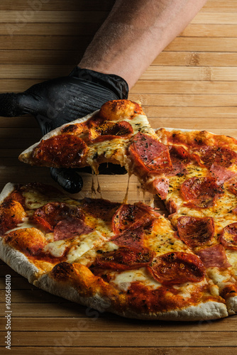 Chef taking a slice of delicious pepperoni pizza