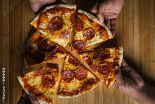 Friends sharing delicious pepperoni pizza on wooden table