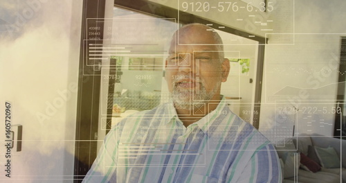 Standing man wearing striped shirt scanning data panels near sliding glass door at living room
