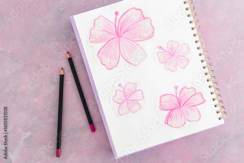sketchpad with pink flower drawings and pencils on a creative desk setup