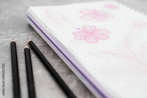 sketchpad with pink flower drawings and pencils on a creative desk setup
