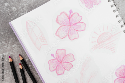 sketchpad with pink flower drawings and pencils on a creative desk setup